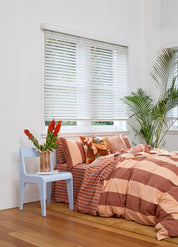 Rust-colored Breeze Quilt Cover Set with bold stripes on a bed